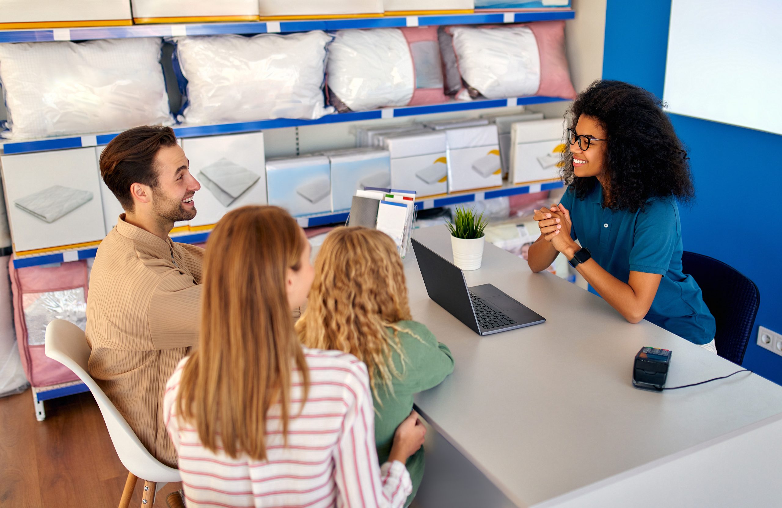 African American woman salesperson consultant assists a young family in the store of beds, mattresses and pillows.